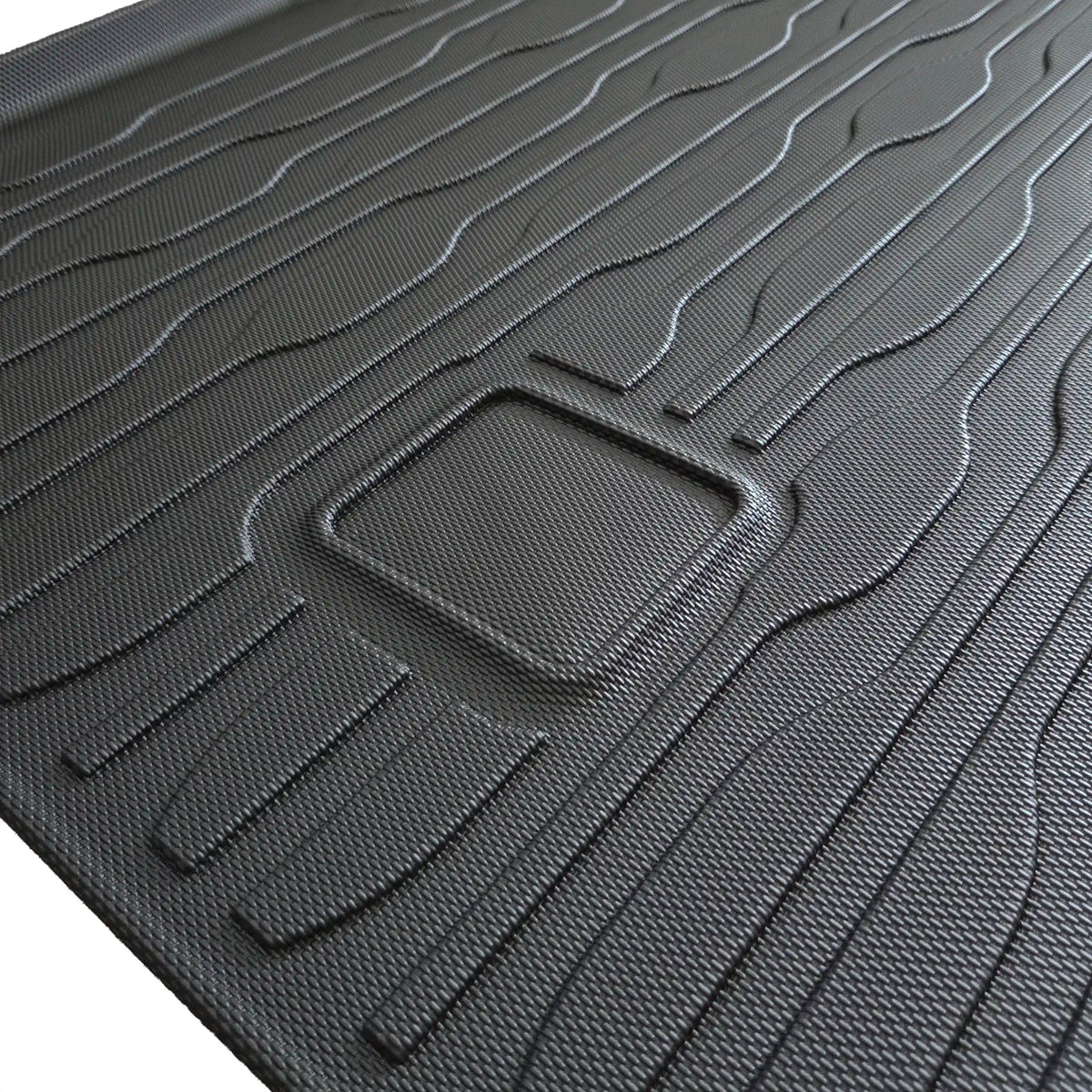 Detailopname van de TPE-kofferbakmat met slijtvaste antislipstructuur en aanduiding van de plaats van de hendel van de onderliggende vloerplaat.